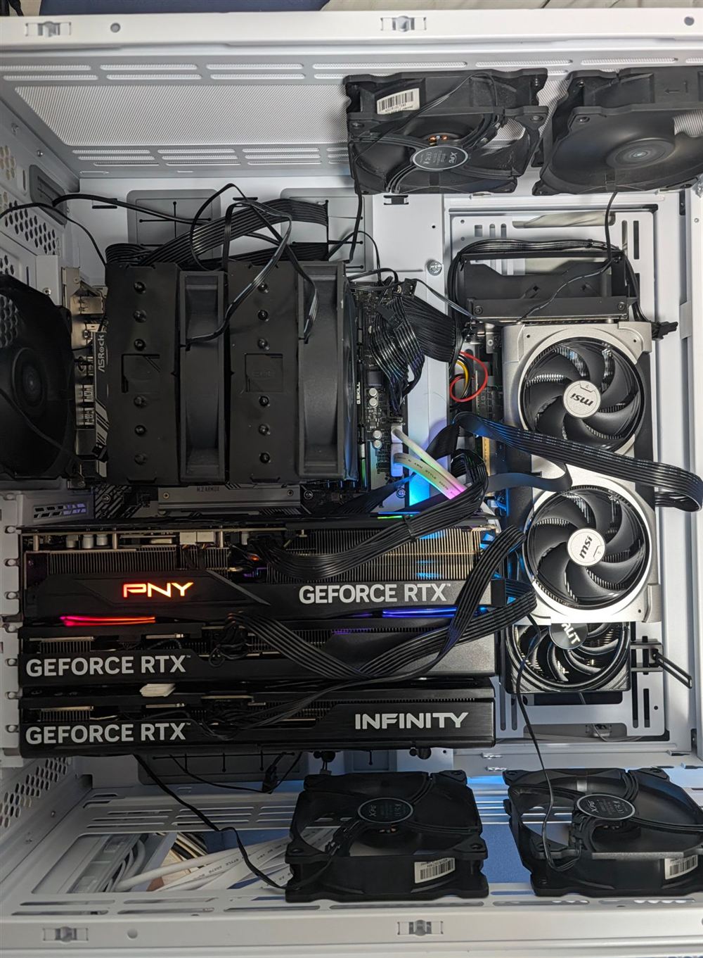 側面パネルを外した PC の内部。左に GPU が横置きで 3 枚、右の縦置きブラケットに 2 枚、中央に大きな空冷 CPU クーラー